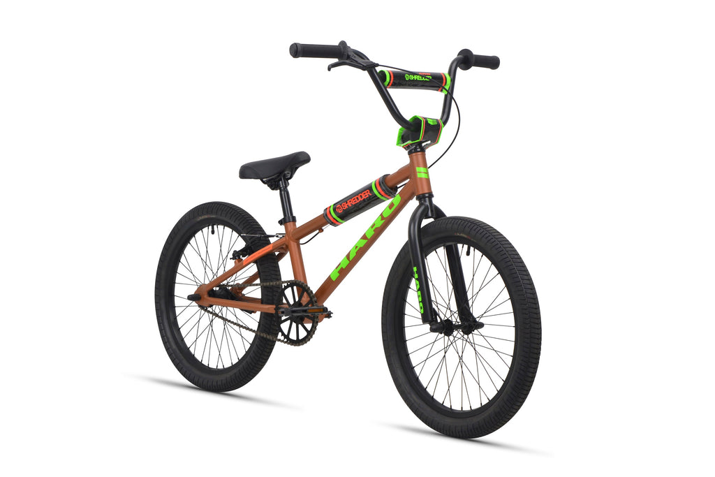 The Shredder 20 BMX bike features a brown alloy frame with green accents, black seat, and black tires.